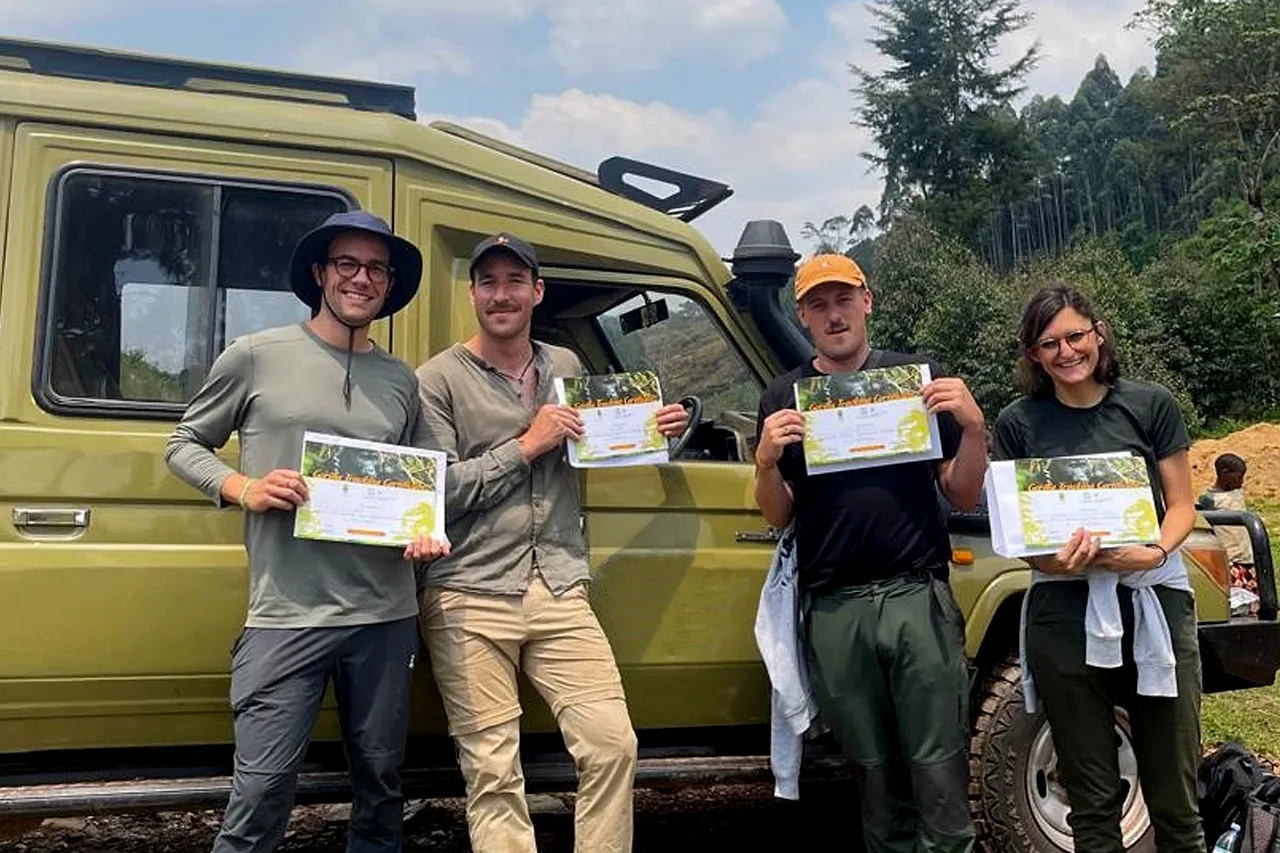 Travellers holding gorilla trekking certificates beside a safari vehicle during a 10 Days Uganda Safari